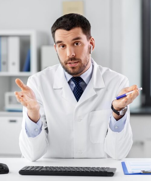 healthcare, medicine and people concept - male doctor with earphones having video conference at hospital