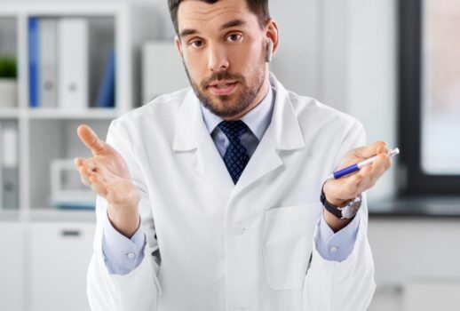 healthcare, medicine and people concept - male doctor with earphones having video conference at hospital